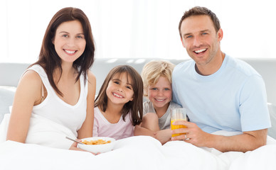 Wall Mural - Cheerful family having breakfast together on the bed