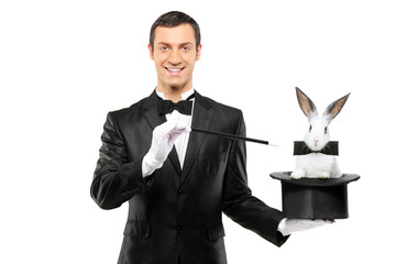 Wall Mural - A magician in a black suit holding a top hat with a rabbit in it