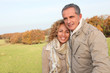 © goodluz - Happy couple walking in country field in autumn