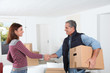 © goodluz - Young woman with removal man holding boxes