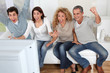 © goodluz - Group of friends sitting in sofa watching sport game on tv