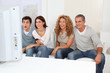 © goodluz - Group of friends sitting in sofa watching sport game on tv