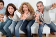 © goodluz - Group of friends sitting in sofa watching sport game on tv