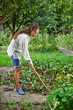 Young woman with hoe working in the garden bed