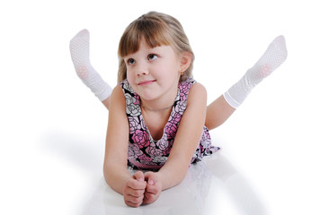 A beautiful little girl lying on the floor. Isolated on the whit