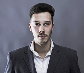 Young attractive man in suit on gray background