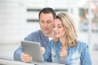 © goodluz - Couple using electronic tab in the street