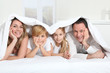 © goodluz - Parents and children laying in bed in the morning