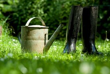Rubber Boots With Watering Can On Grass - Spring Concept