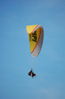 Zwei Menschen mit einem gelben Gleitschirm fliegen in den Himmel