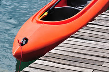 Orange Kayak Floating On Lake Beside Wooden Dock