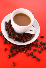 Wall Mural - Small white cup of coffee with coffee grain  on red background