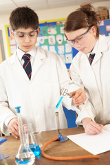 male and female teenage student in science class with experiment