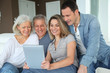 © goodluz - Portrait of happy family sitting in sofa with electronic tablet