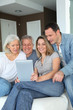 © goodluz - Portrait of happy family sitting in sofa with electronic tablet
