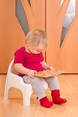 Wall Mural - Adorable baby sit on floor and read small baby book