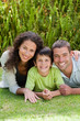 © WavebreakMediaMicro - Little boy with his parents lying down in the garden
