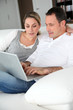 © goodluz - Couple relaxing in sofa with laptop computer