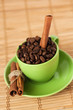 Coffee beans and cinnamon stick in a green cup