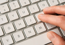 Hand Typing On White Computer Keyboard