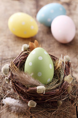 Poster - Green easter egg in nest on wooden background