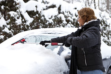 Woman Removing Snow From Car Windshield