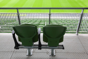 Two green plastic seats on tribune of large stadium