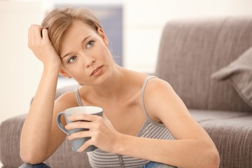 Wall Mural - Young woman thinking with tea in hand