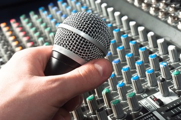 Wall Mural - Part of an audio sound mixer with microphone in hand