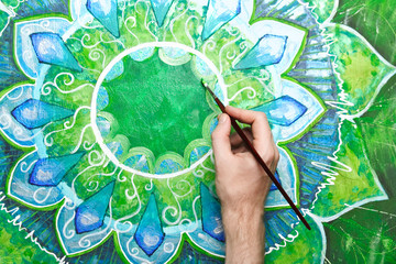 Wall Mural - man painting bright green picture with circle pattern, mandala o