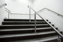 Wide Staircase With Chrome Handrails And Gray Steps, White Walls