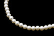 White pearl necklace on black background 