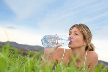  Beautiful blond woman drinking water in natural landscape