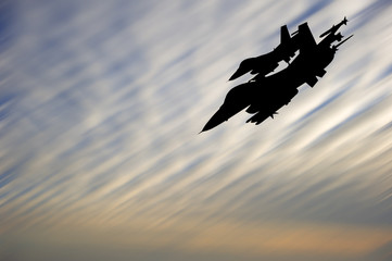 Silhouette of military attack aircraft against vibrant sunset sk