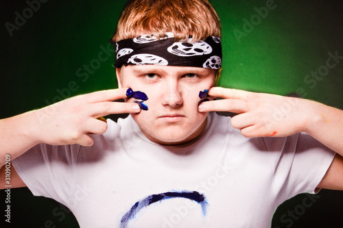 Fotografía Young caucasian man drawing strips on face with blue paint