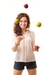 Slim beautiful woman juggling with red and green apples on white