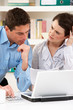 © Monkey Business - Worried Couple Working From Home Using Laptop