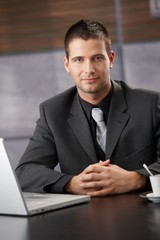 Canvas Print - Confident businessman sitting at meeting table