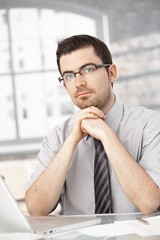 Wall Mural - Portrait of young man sitting at desk using laptop