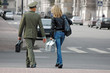 Officer with briefcase and woman with bag crossing a street