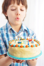 7-year Old Boy Blowing Candles On His Birthday Cake