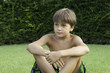Мальчик сидит на зеленой траве