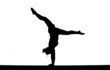 silhouette of female gymnast doing handstand on balance beam