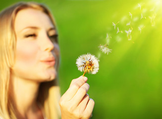 Wall Mural - Happy beautiful girl blowing dandelion