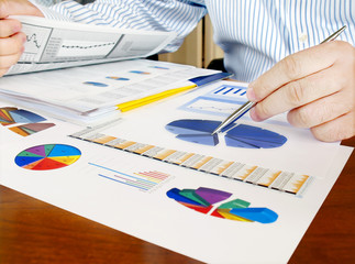 Fototapete - Male hand with pen on the investment charts.