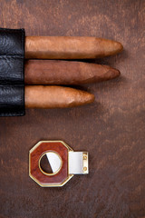 three cigars and cutter on a dark background