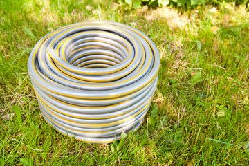 Grey plastic water hose on green grass