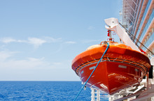 Orange Lifeboat Hanging From Harness Over Deep Blue Sea