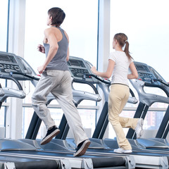 Young woman and man at the gym exercising. Running