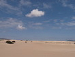 Eine Wolke im Vordergrund in Bildmitte über Wüstensand